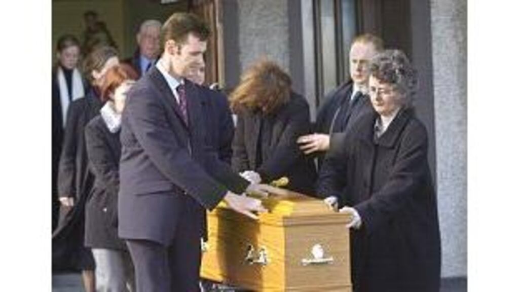 Mr Eamon Traynor, left, and his sister Margaret (right), touch the coffin of their mother, Dublin bus accident victim Ms Margaret Traynor, at the funeral in the Church of Our Lady Immaculate, Darndale, yesterday.