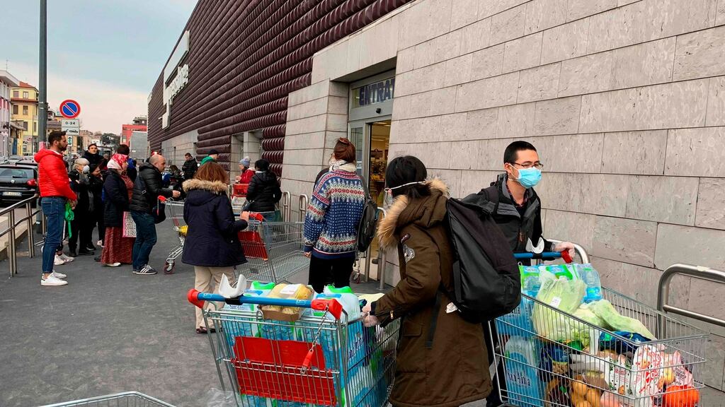 Shoppers in protective masks leave a supermarket with trolleys full of shopping in Milan on Sunday. Photograph: Getty