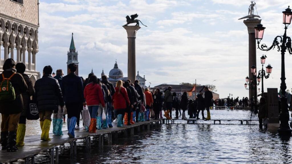 People walk on a footbridge across St Mark’s Square to keep dry. Photograph: Filippo Monteforte/AFP via Getty