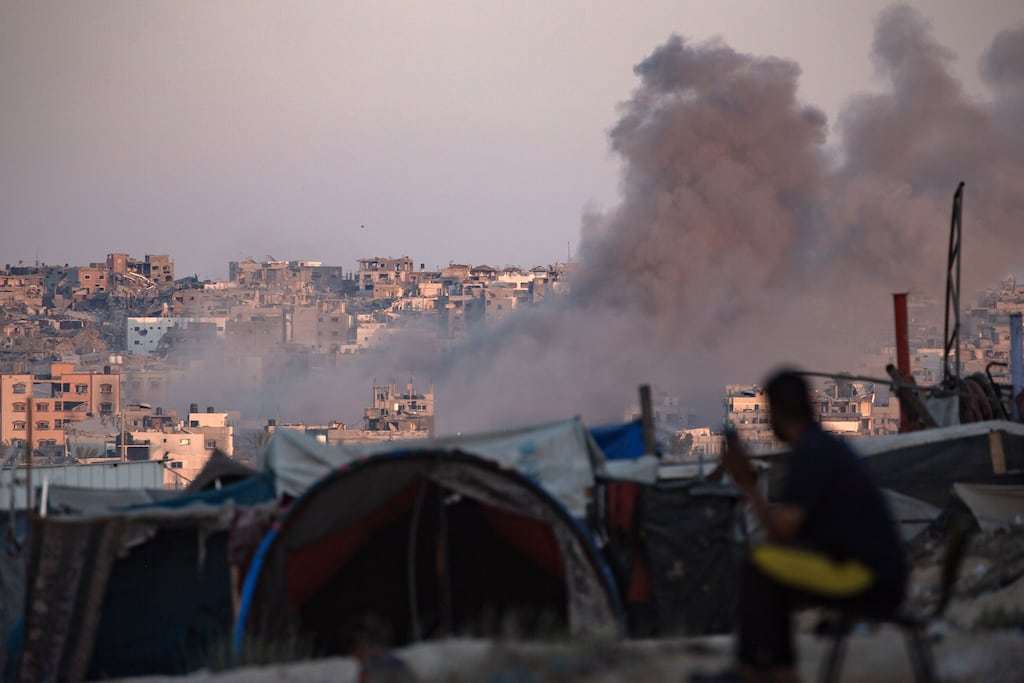 An Israeli air strike as internally displaced Palestinians sit next to their tents in Khan Younis camp, southern Gaza Strip, on Tuesday,