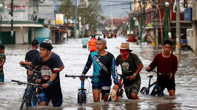 Filipino villagers wade along a flooded road in Nabua. Photograph: EPA