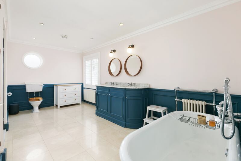 A large en suite with marble flooring, double shower unit and a free-standing cast-iron bath