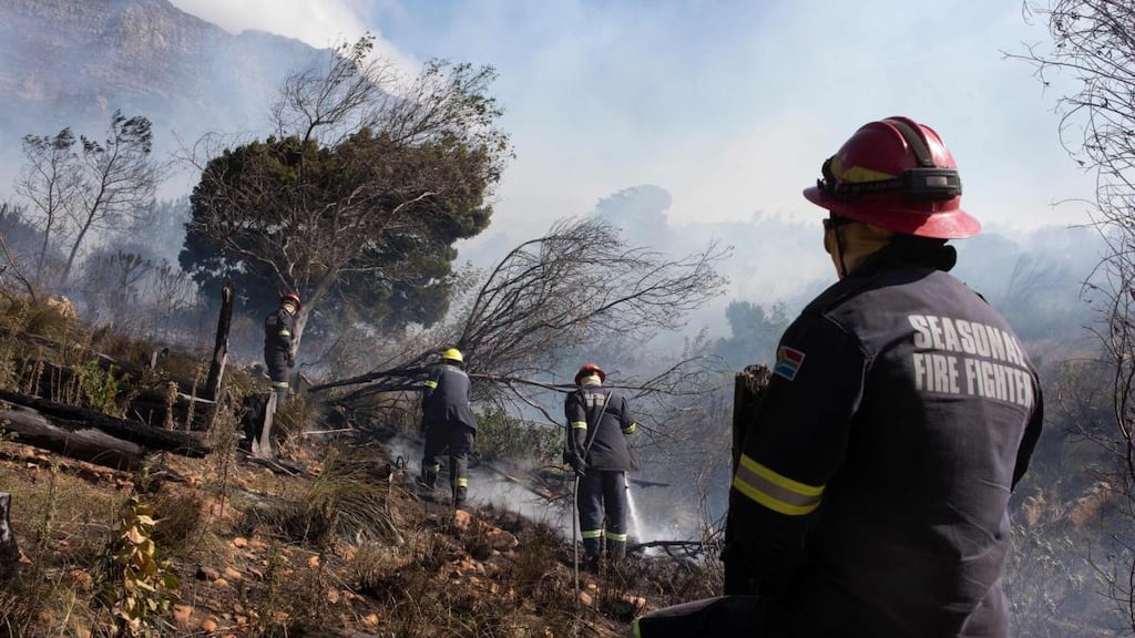 Firefighting teams dampen smouldering vegetation on the foothills of Table Mountain in Cape Town on Monday. Photograph: Rodger Bosch/AFP via Getty Images