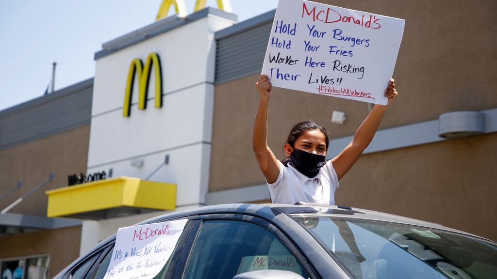 A protester waves a sign from a car during a nationwide strike in the US by McDonald’s workers who claim the company has not done enough to protect them during the coronavirus crisis. Photograph: EUGENE GARCIA/EPA
