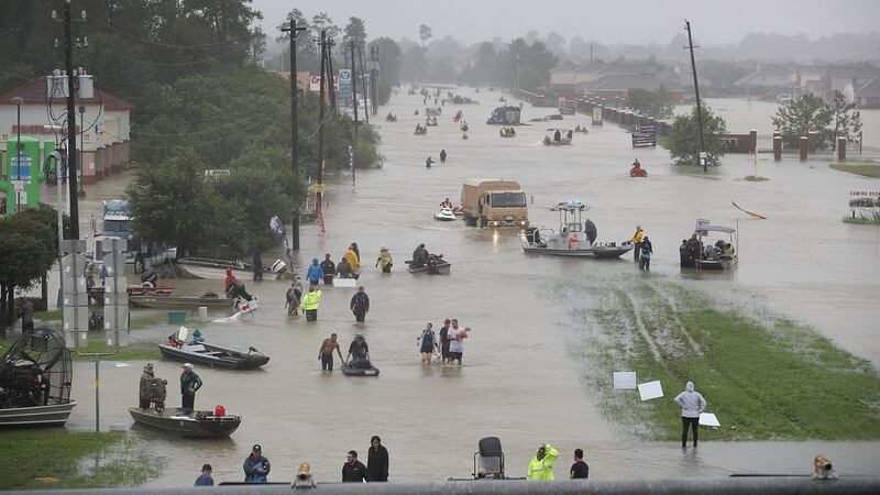 People walk down a flooded street as they evacuate their homes after the area was inundated with flooding from Hurricane Harvey in Houston, Texas. Photograph: Joe Raedle/Getty Images