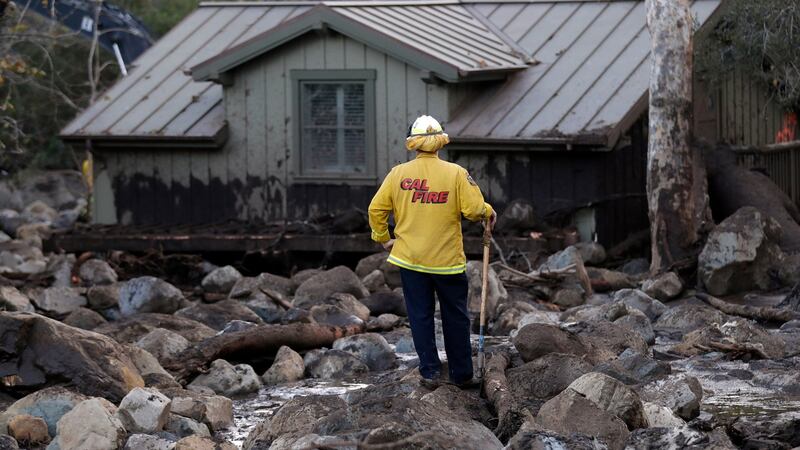 A firefighter walks among the rocks and mud left by a mudslide in Montecito. Photograph: Marcio Jose Sanchez/Reuters