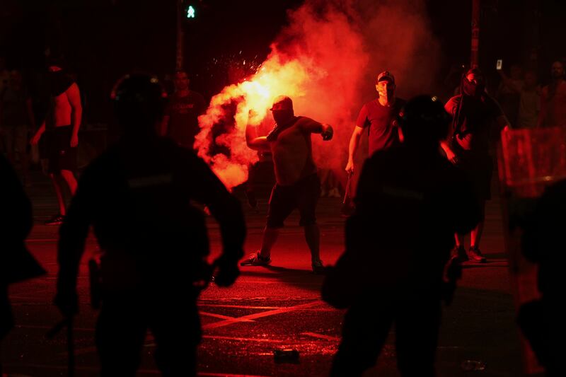 Supporters of Serbian president Aleksandar Vucic hurl flares at protesters during an anti-government protest. Photograph: Darko Vojinovic/AP