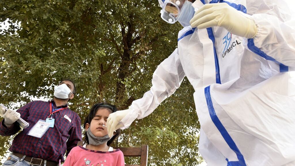 A health worker in PPE kit collects a swab sample from a child for coronavirus testing, at Nirbhay Vihar, Cantonment Area, on October 10th in Lucknow, India. Photograph: Dheeraj Dhawan/Hindustan Times via Getty
