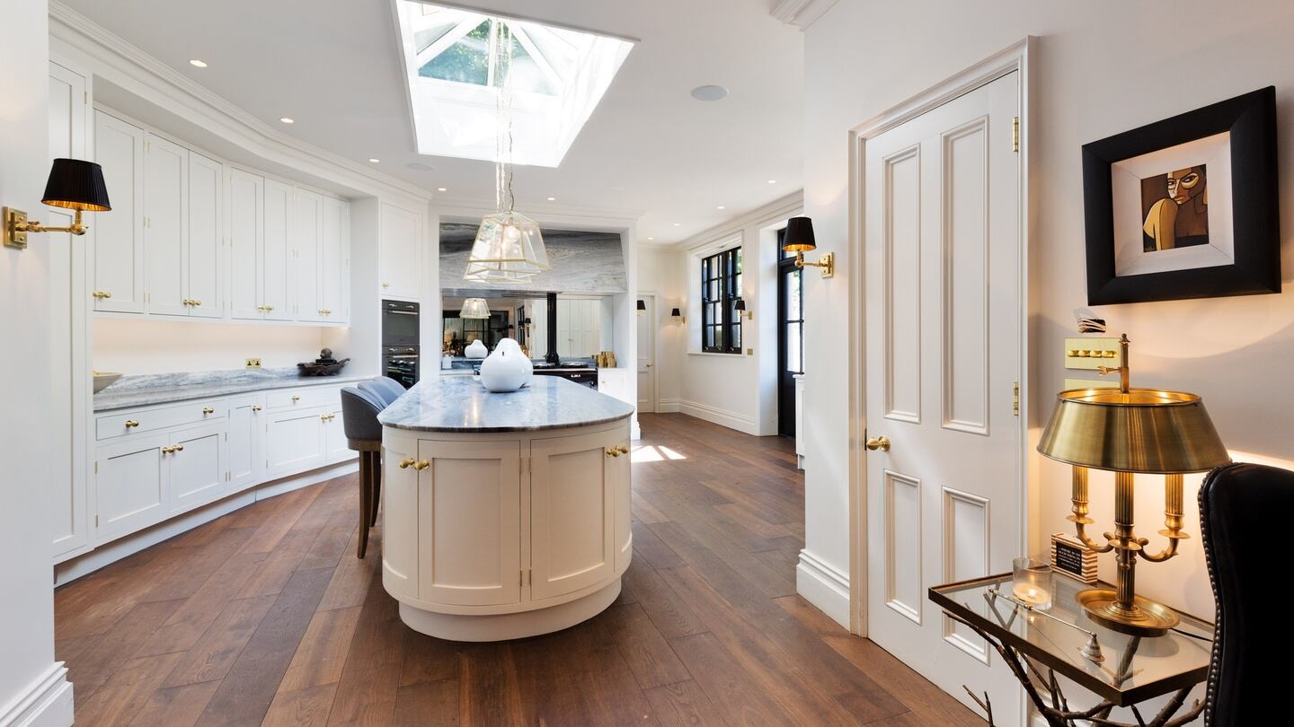 The kitchen is fitted with painted timber units and a stone-topped island unit