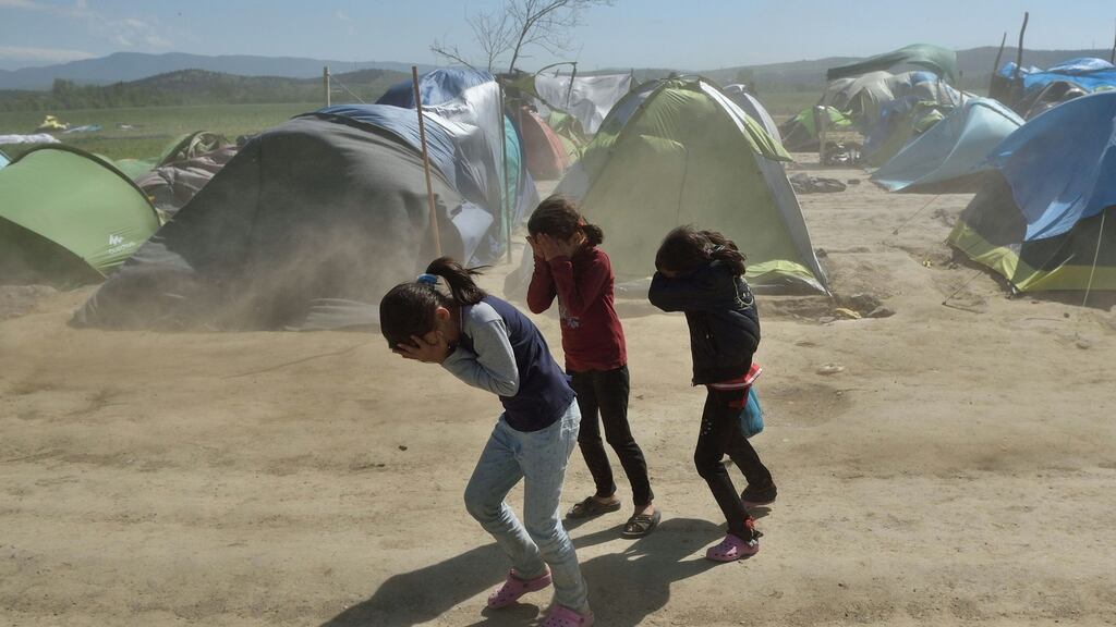 Children cover their faces to protect themselves from dust amid strong winds at a makeshift camp for migrants and refugees at the Greek-Macedonian border near the village of Idomeni on Wednesday. Photograph: Daniel Mihailescu/ AFP/Getty Images