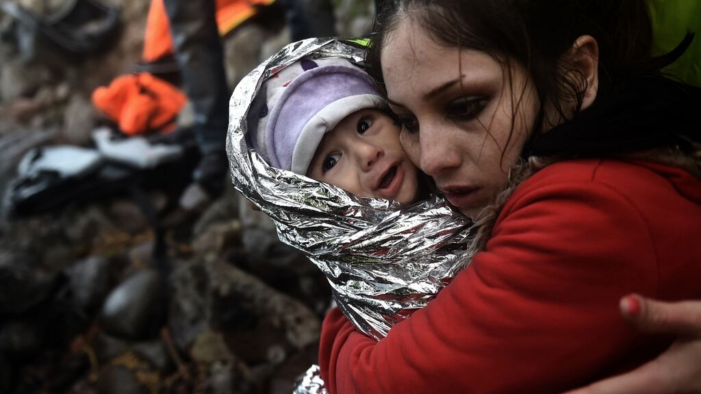 A woman hugs a baby wrapped in an emergency blanket as refugees and migrants arrive on the Greek island of Lesbos after crossing the Aegean sea from Turkey on October 1st, 2015. Photograph: Aris Messinis/AFP/Getty Images