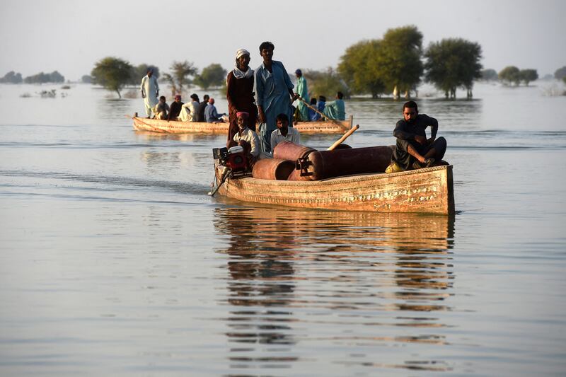 Internally displaced people use boats to cross a flooded area in Sindh province, Pakistan, in October 2022. Photograph: Asif Hassan/AFP via Getty Images