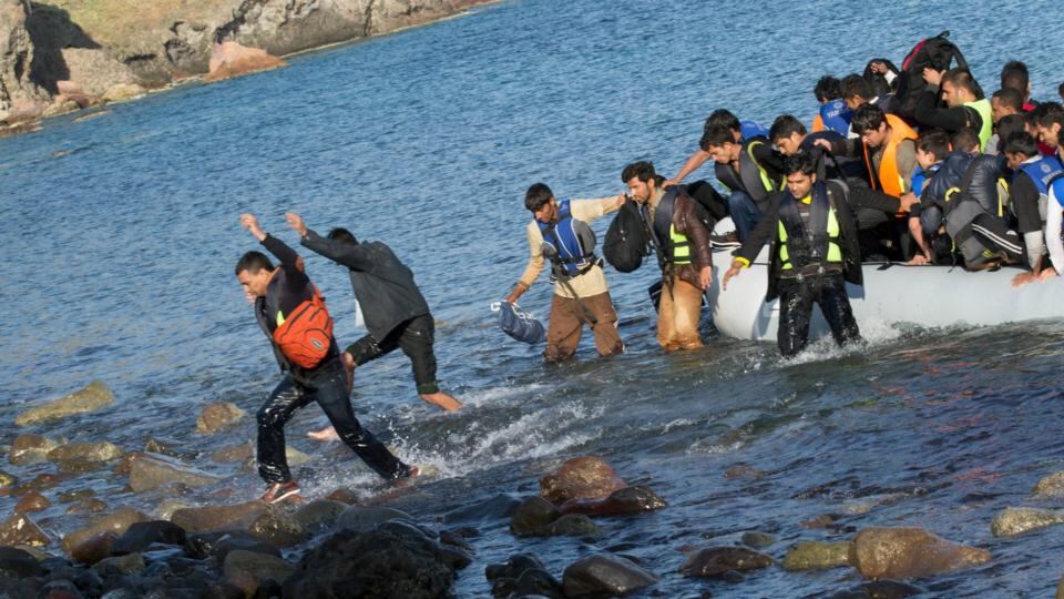 An inflatable boat with migrants from Somalia, Afghanistan and Pakistan arrives at Molyvos, on the Greek island of Lesvos, on Tuesday. As it approaches the rocky shore, the boat’s passengers leapt out into the water, delighted to finally step foot in the European Union. Photograph: Nikolas Georgiou