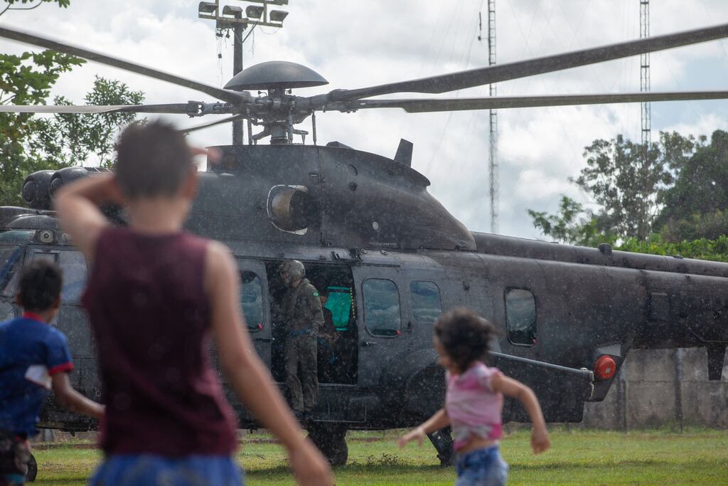 Children play next to a Brazilian Army helicopter taking part in the search for missing indigenist Bruno Pereira and journalist Dom Phillips, in the municipality of Atalaia do Norte, state of Amazonas, Brazil on Friday. Photograph: Joao Laet/AFP via Getty Images