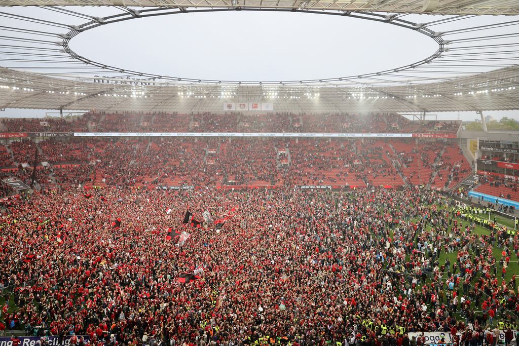 Fans of Bayer Leverkusen invade the BayArena pitch after their team's victory over Werder Bremen secured a first Bundesliga title. Photograph: Andreas Rentz/Getty Images
