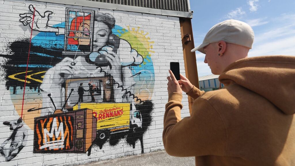 A man photographs a street art mural by the artist ADW in Portarlington, Co Laois. Entitled ‘Is it Still raining? I hadn’t noticed’, the work deals with the issue of mental health during the Covid-19 lockdown. Photograph: PA