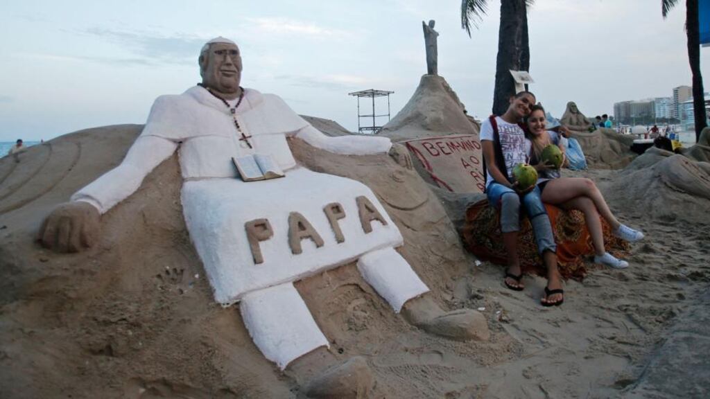 Tourists pose in front of a sand sculpture of Pope Francis at Copacabana beach in Rio de Janeiro yesterday. The pope  will spend a week in the city to preside over the Catholic Church’s 28th World Day of Youth. Photograph: Reuters/Sergio Moraes