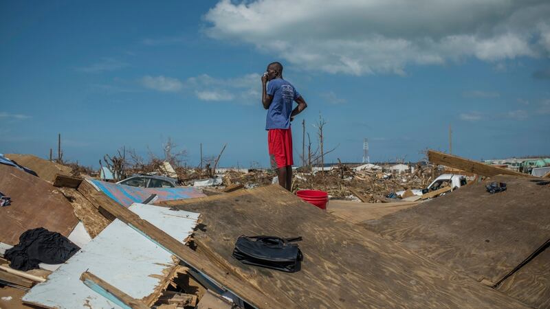 Herbert Luberal covers his nose against the smell from bodies in Marsh Harbour. Photograph: Daniele Volpe/The New York Times