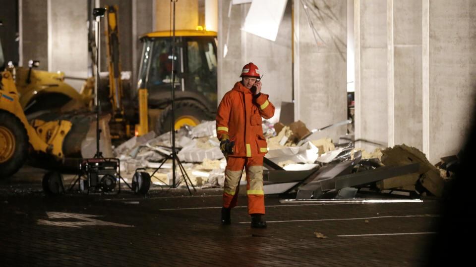 An emergency service personnel speaks on his mobile phone as he walks past rubbles from the collapsed Maxima supermarket in Riga.