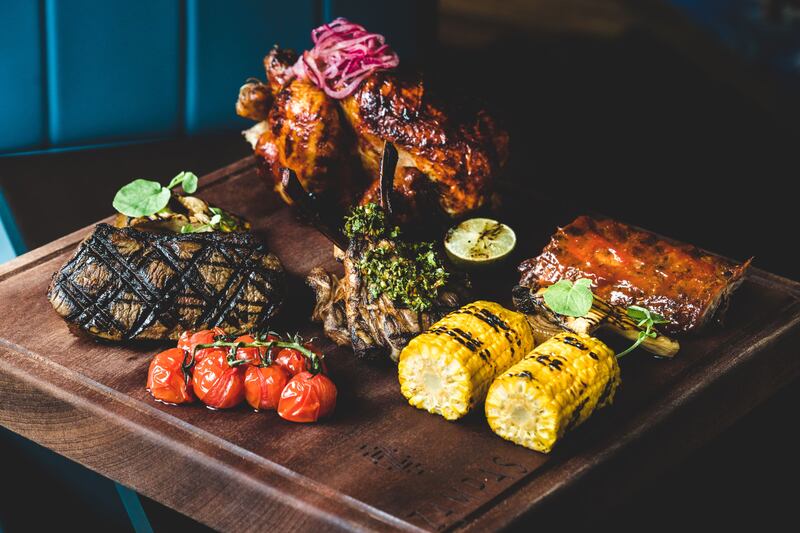 The Zampas Butchers Block, a belly buster that features an asador-roasted chicken, sirloin steak, tonkatsu pork ribs and smoked lamb tomahawks plus sides and sauces