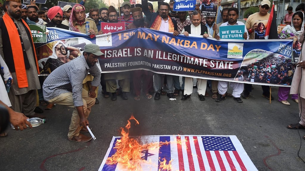 Supporters of Palestine Foundation Pakistan burn Israel and US flags and display placards of slain journalist Shireen Abu Akleh in Karachi. Photograph: Rizwan Tabassum/AFP