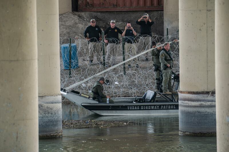 Law enforcement officers stand near concertina wire on the bank of the Rio Grande river. Photograph: Go Nakamura/New York Times