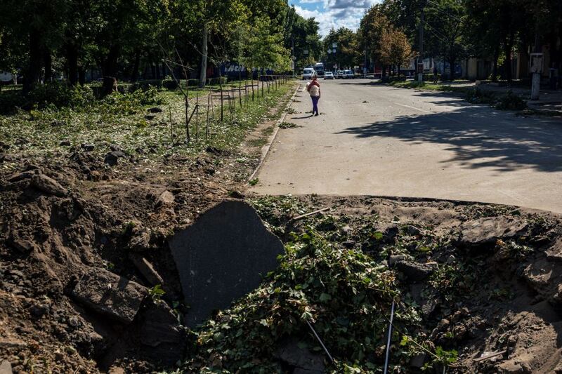 A woman walks down a street behind a crater following a missile strike in Mykolaiv, Ukraine. Photograph: Dimitar Dilkoff/AFP via Getty Images