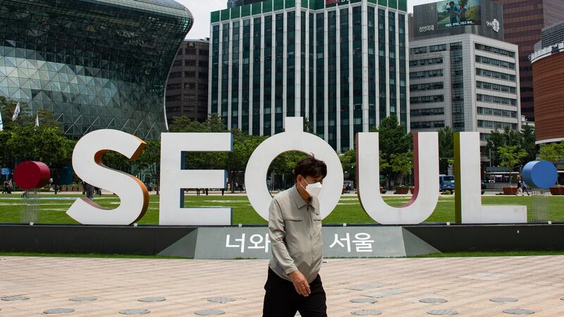 A man wearing a face mask walks past Seoul city hall on Tuesday. Millions of students throughout the country are expected to return to school on Wednesday. Photograph: EPA