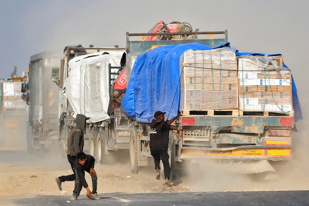 A Palestinian man attempts to climb on a truck travelling along Salah al-Din road in the central Gaza Strip, near Deir al-Balah, as people attempt to obtain humanitarian aid. Photograph: Eyad Baba/AFP/Getty Images