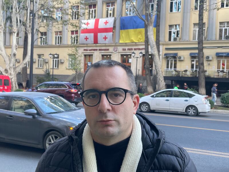 Egor Kuroptev, Georgia-based director of the Free Russia Foundation in the South Caucasus, pictured with Georgian and Ukrainian flags hanging on a university building in central Tbilisi. Photograph by Daniel McLaughlin