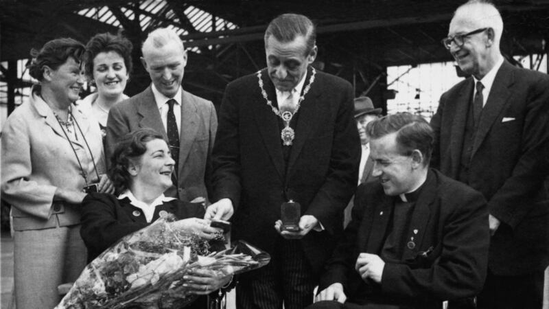 Joan Horan, Ireland’s first female Paralympian and first gold medal winner, and team captain Fr Leo Close at Dublin Airport after returning from Rome. Horan appears to be showing her medals to Deputy Mayor Robert Briscoe. Photograph: Irish Wheelchair Association