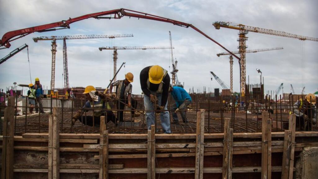 Workers labour as cranes operate at the construction site of Lisboa Palace, developed by SJM Holdings, in Macau, China. Photographer: Lam Yik Fei/Bloomberg