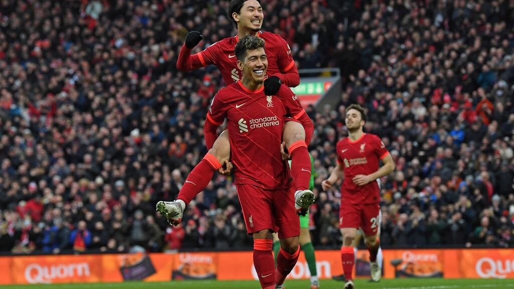 Takumi Minamino jumps on the back of Roberto Firmino as he celebrates scoring against Brentford at Anfield. Photograph: Getty Images