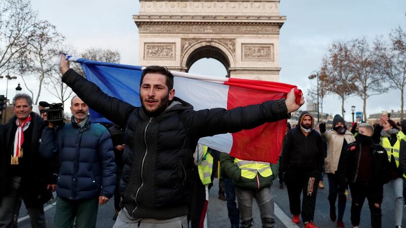 A protester holds the French flag as he walks with others wearing yellow vests. Photograph: Benoit Tessier/Reuters