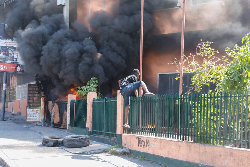 A man climbs over a fence outside the offices of Haiti’s power company, which was set on fire during protests. Photograph: Odelyn Joseph/AP