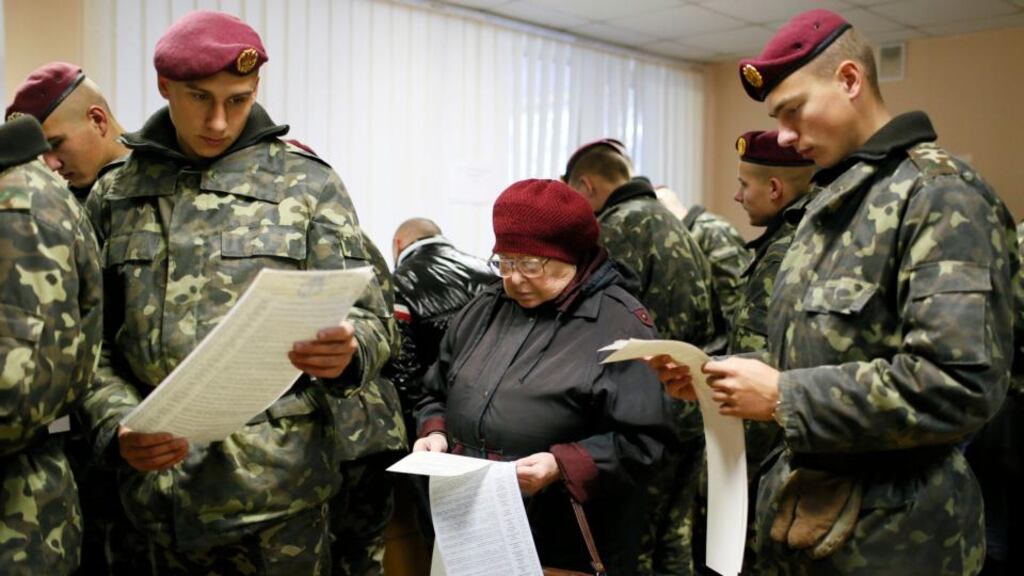 Ukrainian servicemen and a woman hold their ballots during a parliamentary election at a polling station in Kiev. Ukrainians voted yesterday in an election that is expected to strengthen President Petro Poroshenko’s mandate to end a separatist conflict in the east of the country. Photograph: Reuters