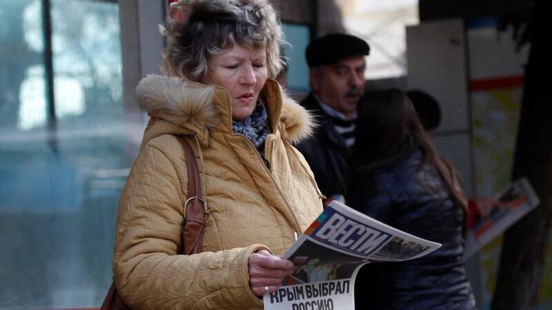 A woman reads a free newspaper with the headline ‘Crimea chooses Russia’ on a street in Simferopol, Crimea. Photograph: Vasily Fedosenko/Reuters