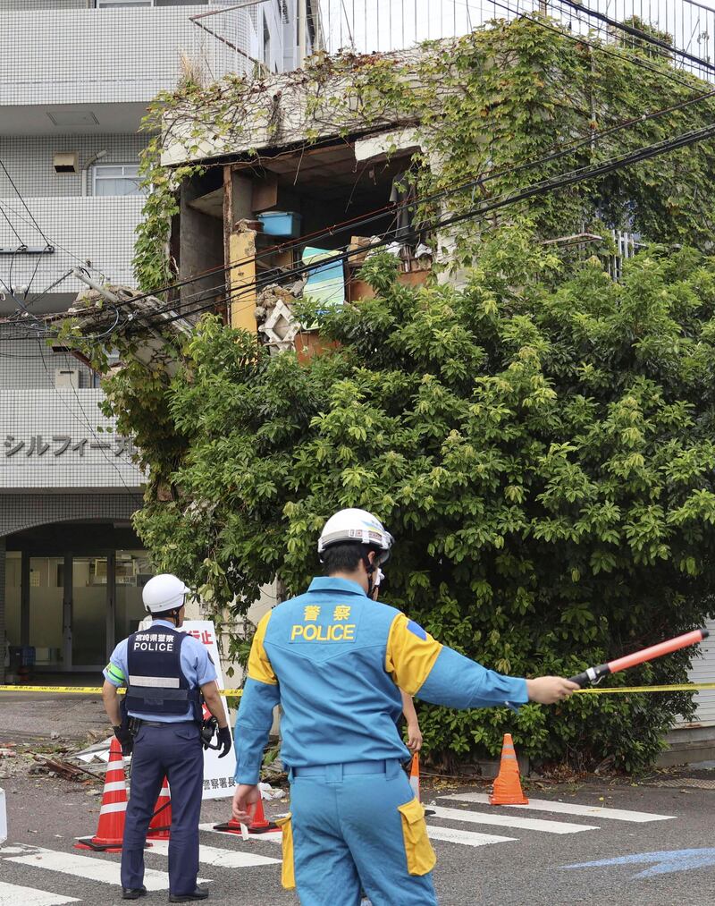 Police stand outside a damaged building in Miyazaki, western Japan, following the earthquake. Photograph: Kyodo News/AP