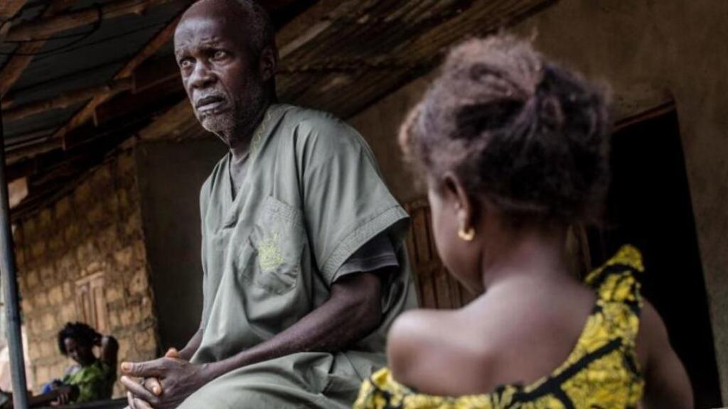 Foday Ansumana Konneh, who reportedly lost family members to Ebola, with his grandchildren, in the village of Njala Giema, Sierra Leone. Photograph: Tommy Trenchard/The New York Times