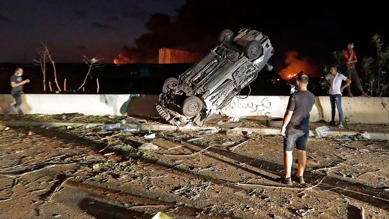 People gather by destroyed cars. Photograph: Joseph Eid/ AFP via Getty Images