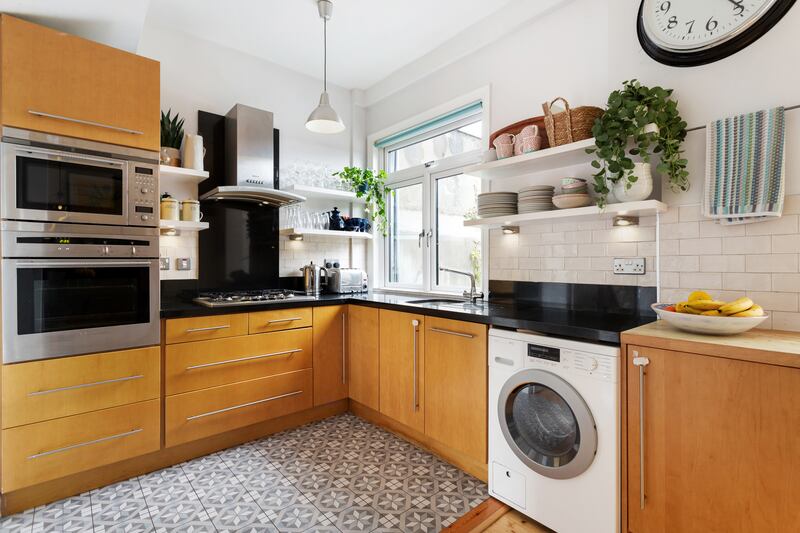 The kitchen, at the end of the hall, has wooden fittings, open shelving and a neutral, Moroccan-style tiled floor. Photograph: Keith Owens