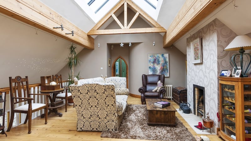 The livingroom is upstairs, with a large arched window and roof lights in its tall pitched ceiling which features exposed beams