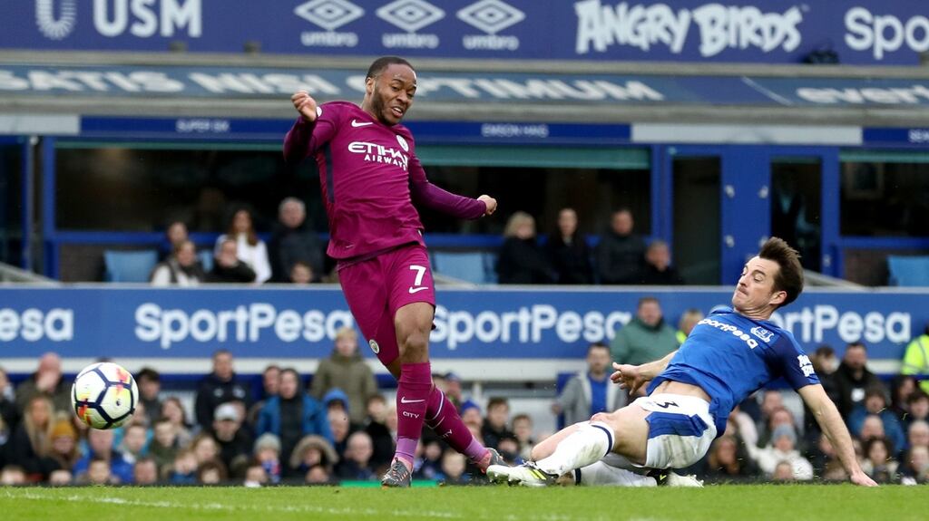 Manchester City’s Raheem Sterling scores his side’s third goal despite the challenge of Everton’s Leighton Baines during the Premier League match at Goodison Park. Photograph: Tim Goode/PA Wire