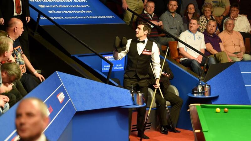 Ronnie O’Sullivan asks the crowd for a lend of a pair of shoes after playing in his socks due to the tightness of the pair he was wearing. He eventually borrowed a pair from tournament director Mike Ganley. Photo: Martin Rickett/PA Wire