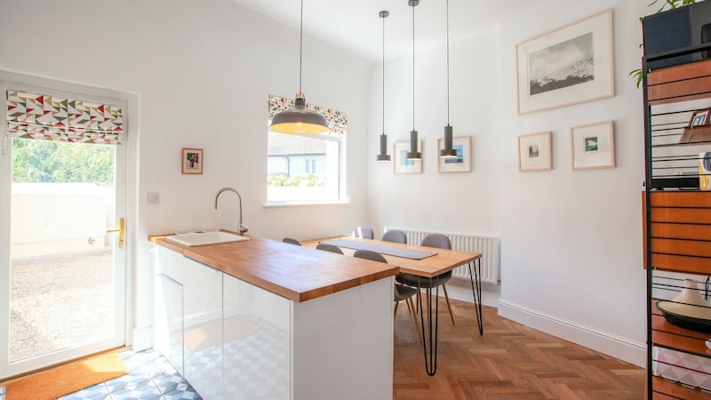 The eat-in kitchen has smart white Ikea units and timber countertops with a neat island dividing the dining table from the worktops
