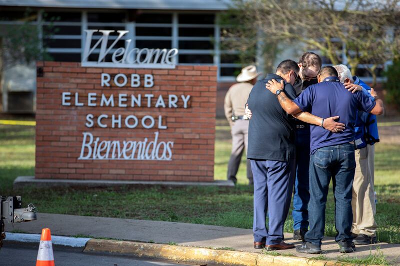 Men pray outside Robb Elementary School in Uvalde, Texas. Photograph: Ivan Pierre Aguirre/The New York Times