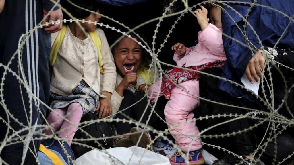 A little girl cries as she tries to take shelter from the rain on Greece’s border with Macedonia, as she waits with her family to enter Gevgelija on Saturday. Photograph: Reuters