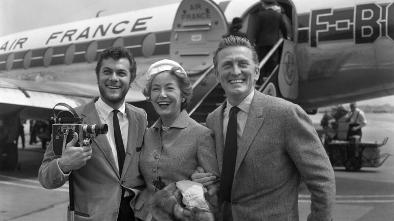 A 1957 file photograph of Kirk Douglas and his wife Anne Buydens being met by Tony Curtis, left, on their arrival at London Airport from Paris. Photograph: PA Wire.