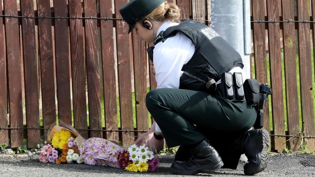 A police officer lays flowers passed to her by members of the public at the scene where journalist Lyra McKee was fatally shot in Derry. Photograph: Paul Faith/AFP/Getty Images