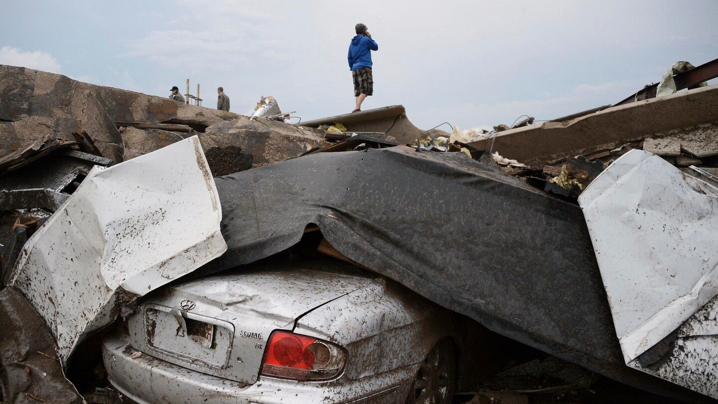 A damaged car is seen as a resident stands on top of wreckage after a tornado struck Moore, Oklahoma. Photograph: Gene Blevins/Reuters